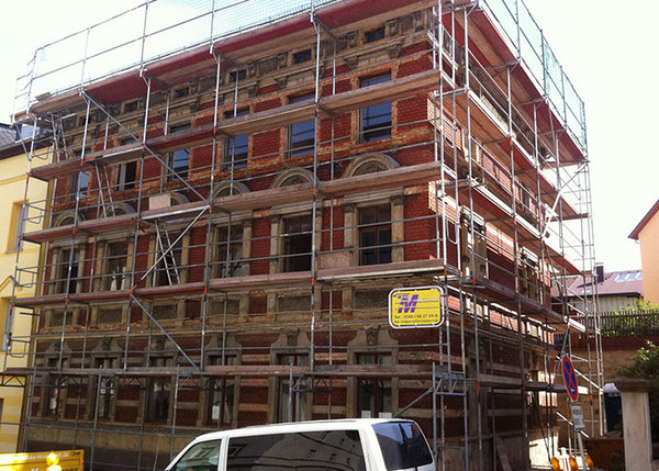 Historisches Gebäude mit Backsteinfassade und Baugerüst für Fassadensanierung.