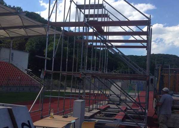 Gerüstbau auf Sportplatz mit Tribüne, Bauarbeiten und temporärer Zuschauertribüne im Freien.